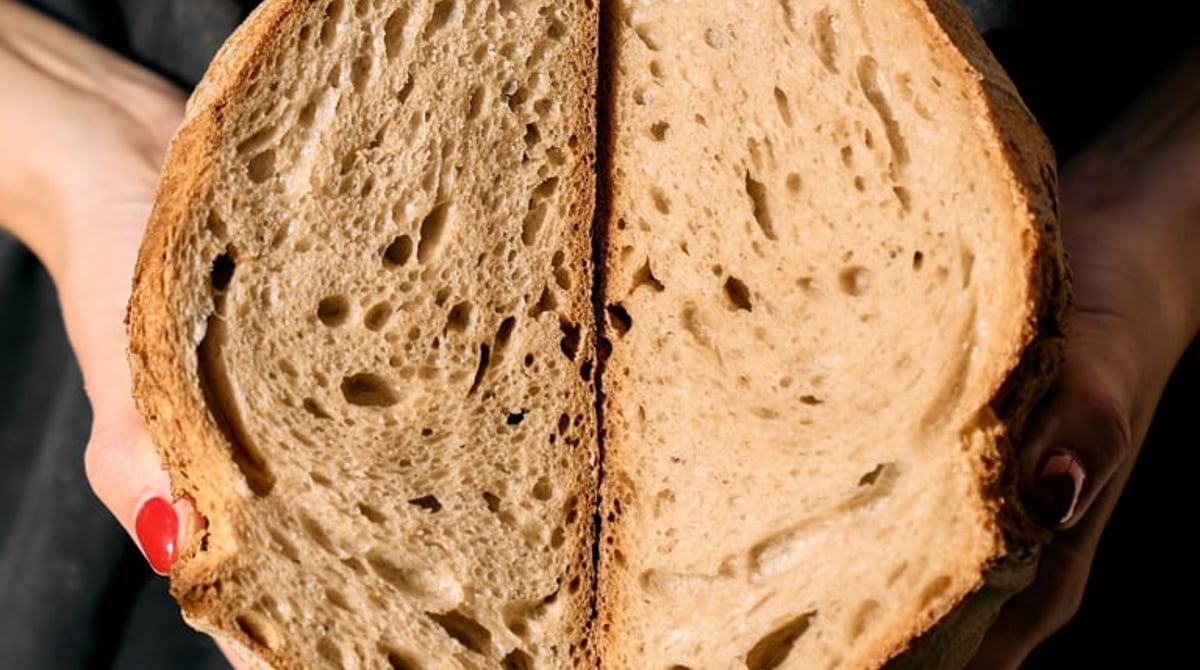 Aufgeschnittenes Sauerteigbrot, das ein Bäcker mit beiden Händen hält