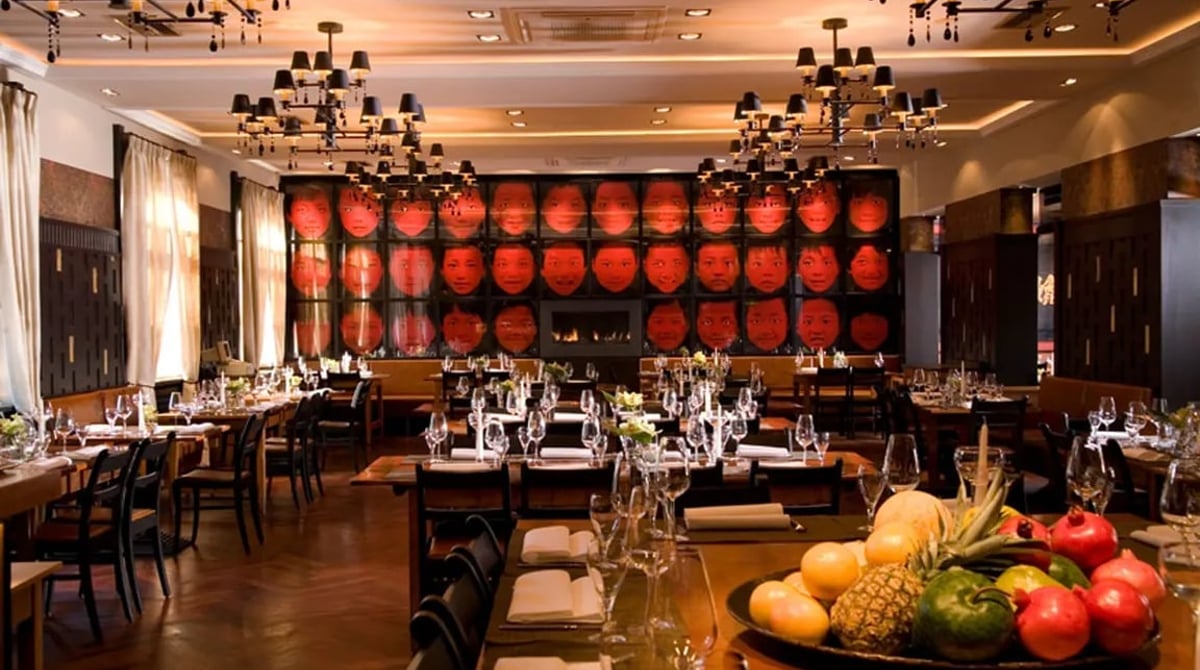 Hauptrestaurant des Mangostin Asia in Thalkirchen mit gedeckten Tischen, Kronleuchtern und roter Wandfläche