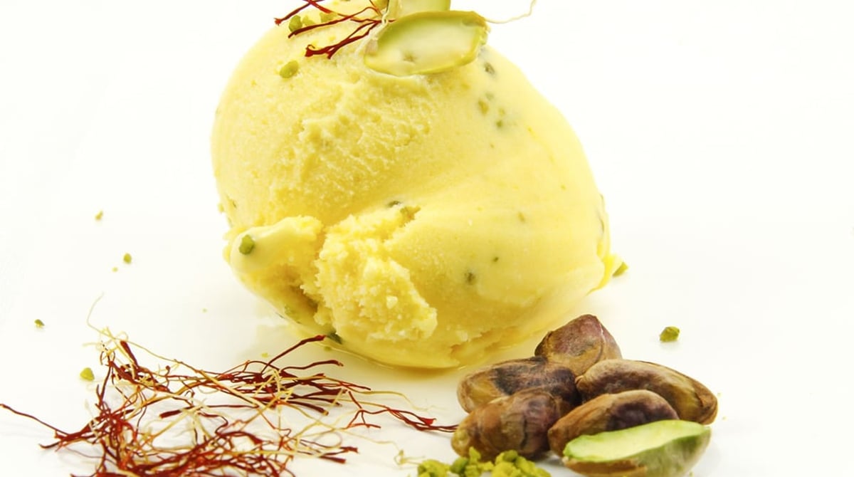 Eiskugel Safran-Pistazie mit Safranfäden und Pistazien auf weißem Grund