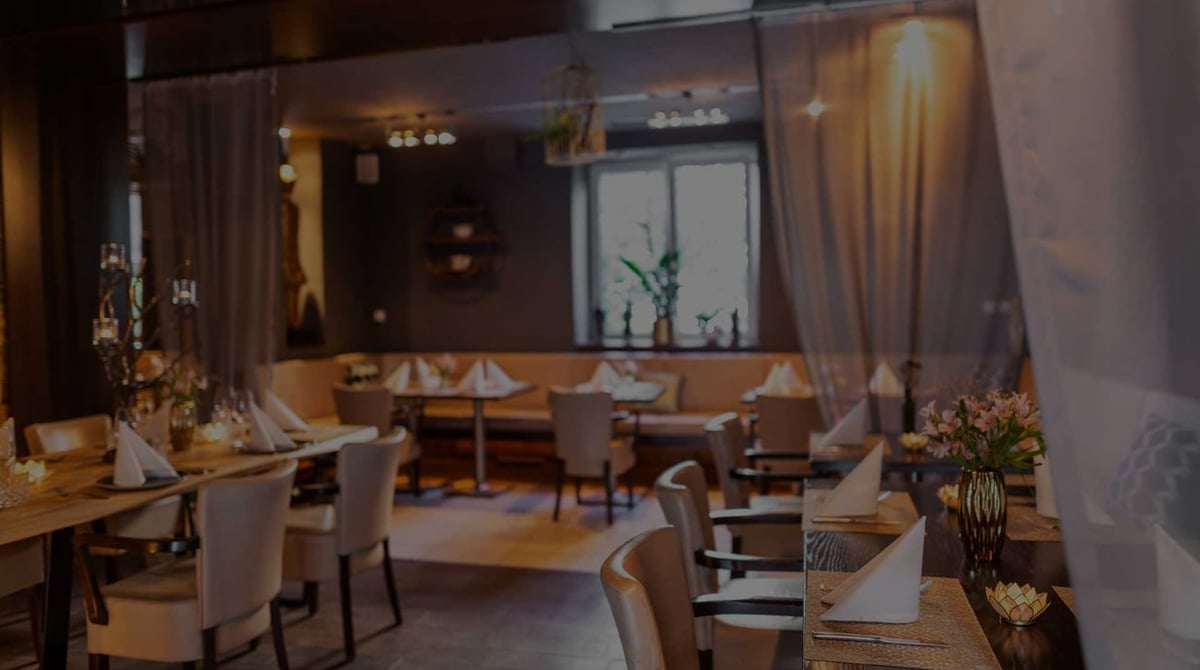 Gastraum des Sumi Panasia Kitchen mit gedeckten Tischen, hellen Vorhängen und Sitzbank in München-Neuhausen