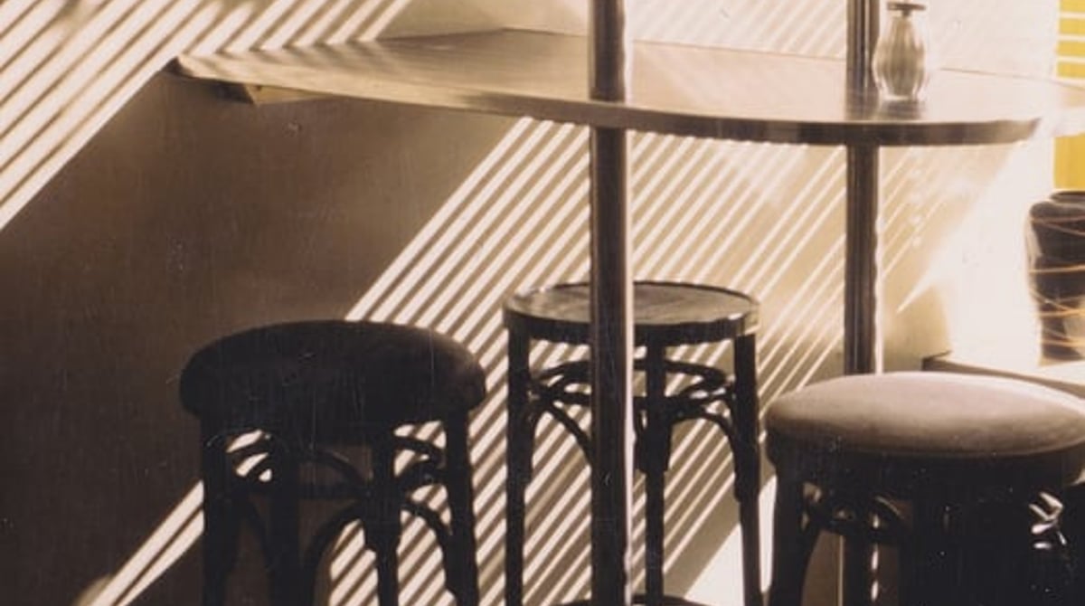 Barhocker an einem Stehtisch im Baader Café, auf dem Boden fällt Streiflicht durch die Fenster