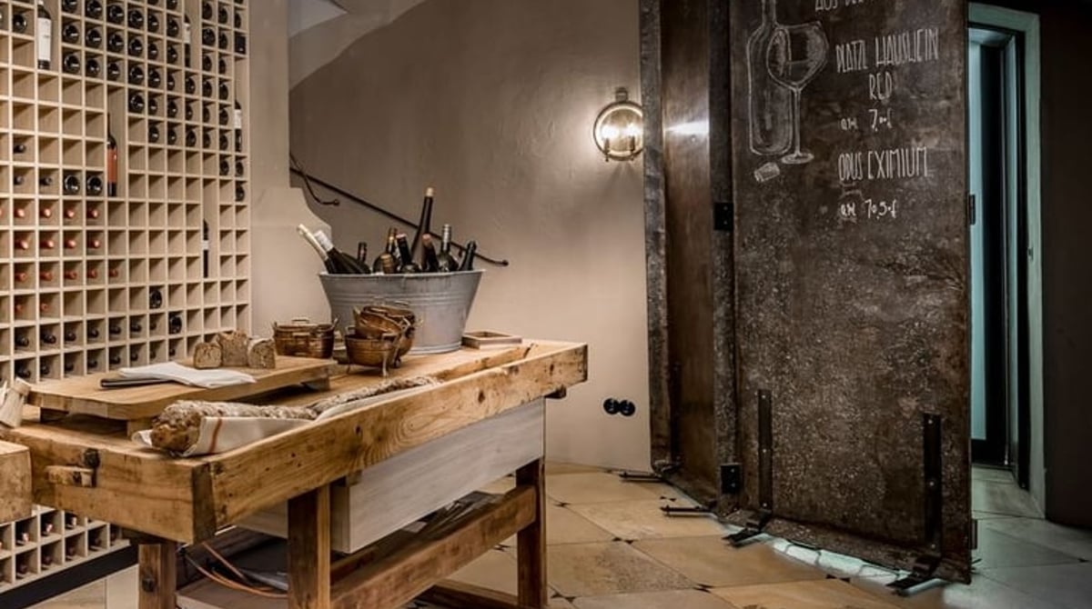 Raum mit Holzwerkbank, Weinregal und Leuchter in der Pfistermühle