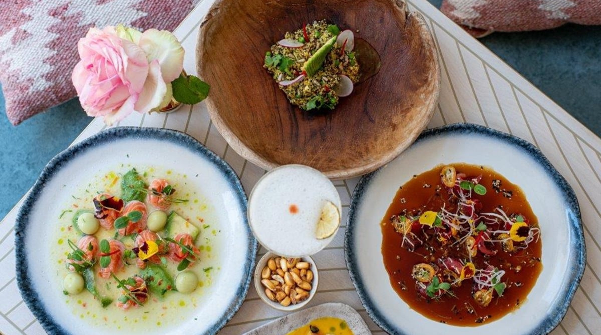 Gedeckter Tisch der Cevicheria Pez mit mehreren Ceviches, Cancha und Pisco-Cocktail