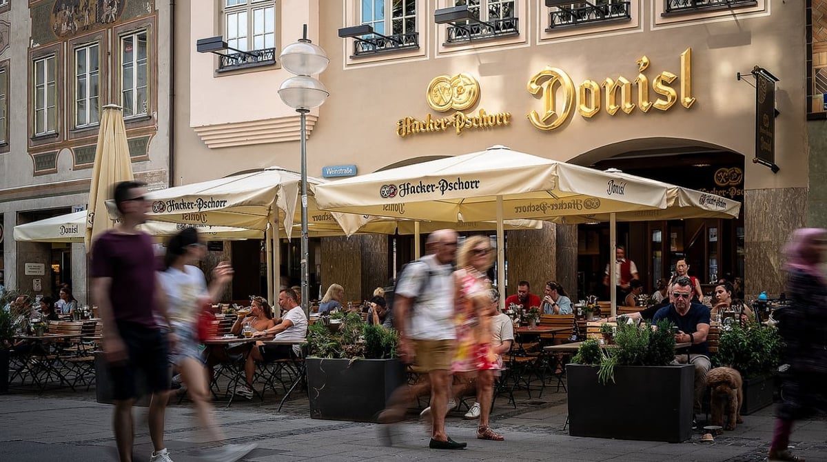 Außenansicht des Donisl an der Weinstraße am Marienplatz mit Tischen und Sonnenschirmen vor dem Haus