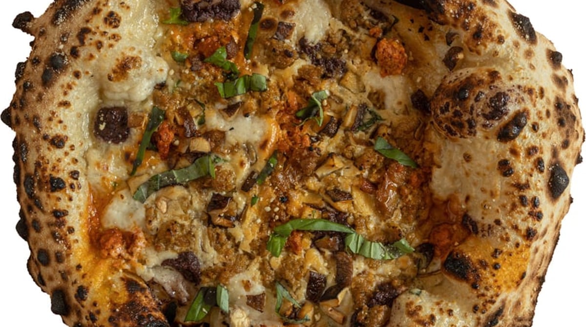 Vegane Pizza von Dr. Drooly mit gebräuntem Rand auf rosa Untergrund