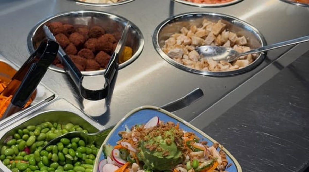 Fertige Bowl auf der Zutatentheke mit Lachs, Tofu, Edamame und Gemüse