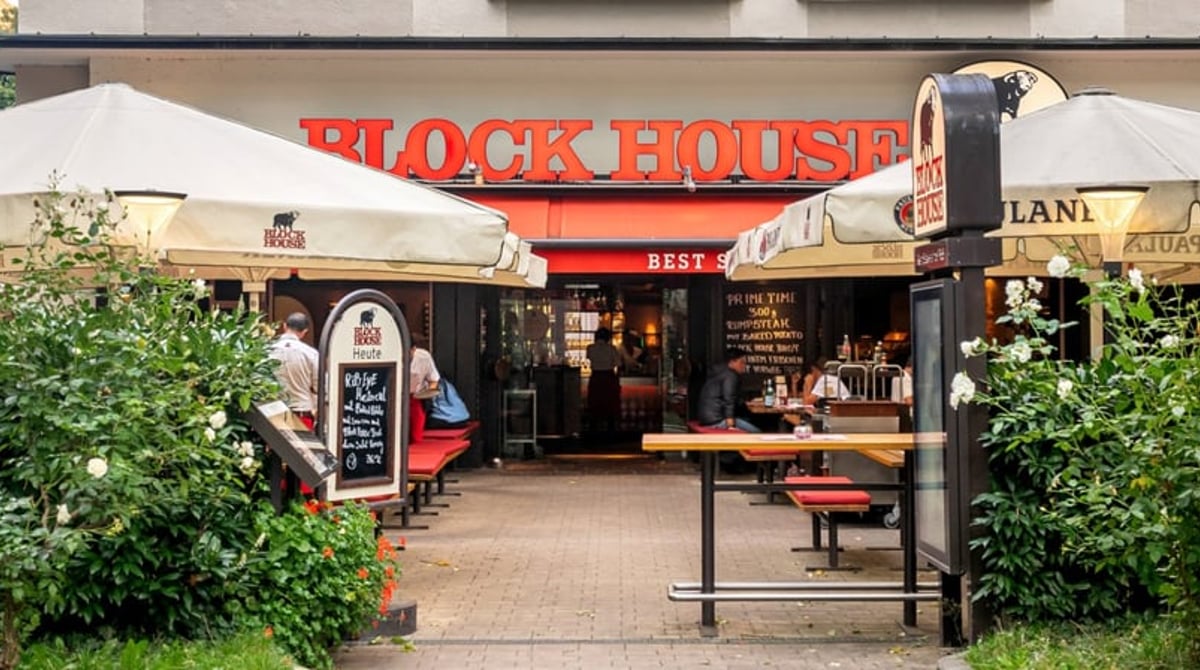 Eingang und Terrasse des Block House an der Leopoldstraße mit Sonnenschirmen und Gästen