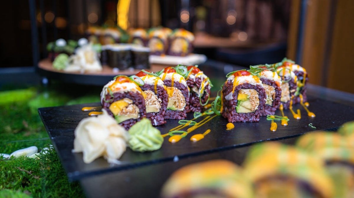 Bunte vegane Rolls mit violettem Reis auf einer Schieferplatte