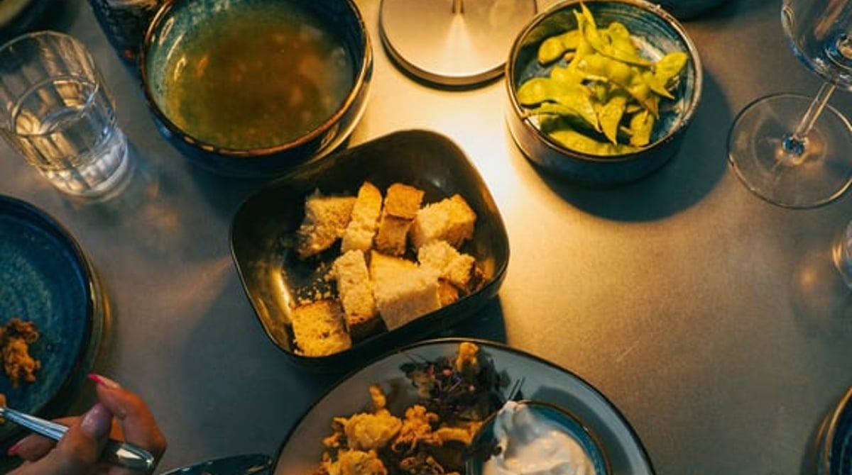 Geteilte Teller mit frittiertem Fisch, Suppe, Edamame und Brot auf einem Tisch im Tuna Fish Club