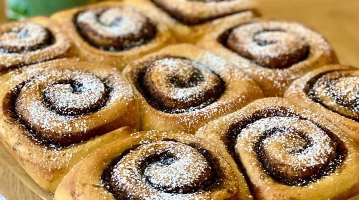 Zimtschnecken mit Puderzucker auf einer Kuchenplatte