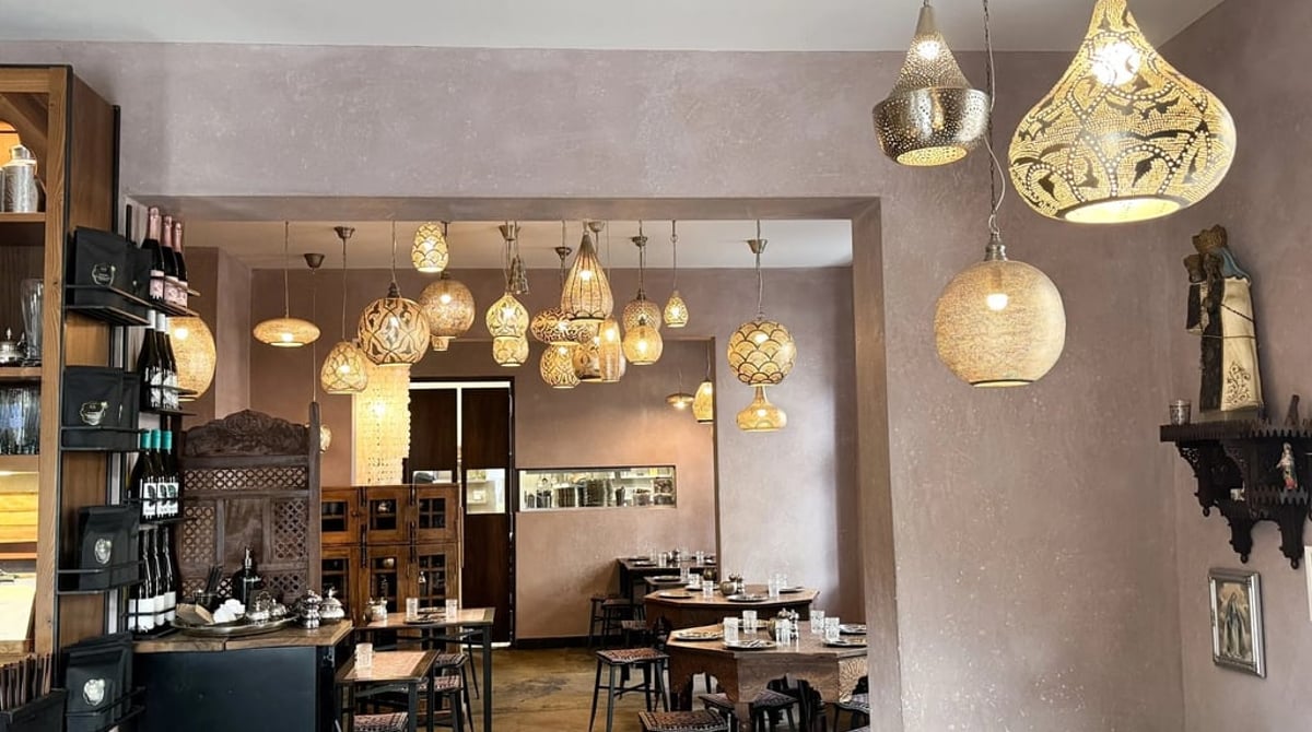 Gastraum des maria mit goldenen orientalischen Hängelampen, dunklen Holztischen und einem Regal mit Flaschen