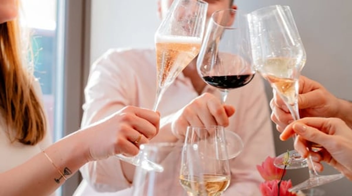 Gäste stoßen an einem Tisch mit Tapas und Wein an