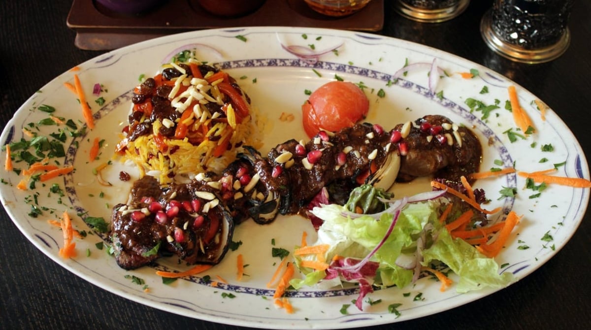 Gegrilltes Fleisch mit Granatapfelkernen, Mandeln und Safranreis im Shandiz
