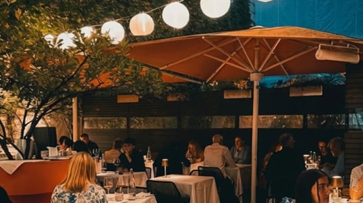 Abendlich beleuchtete Terrasse im Innenhof des Pageou mit Papierlaternen und Sonnenschirm