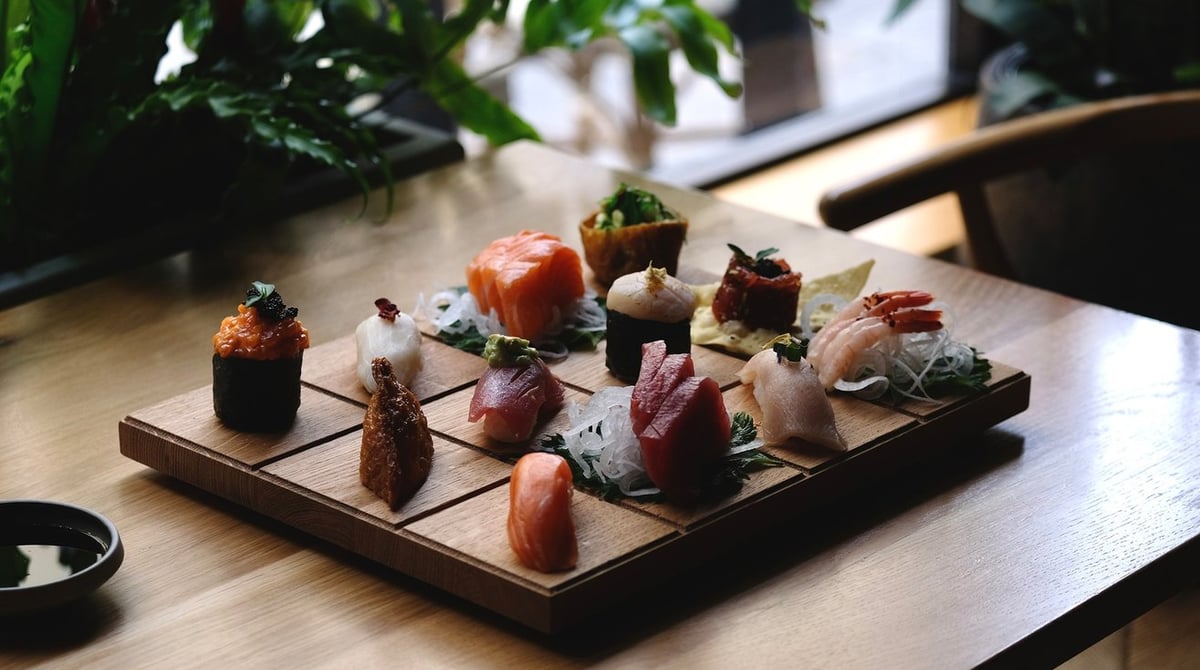 Sushi-Auswahl auf einem Holzbrett an einem Tisch im UKIYO