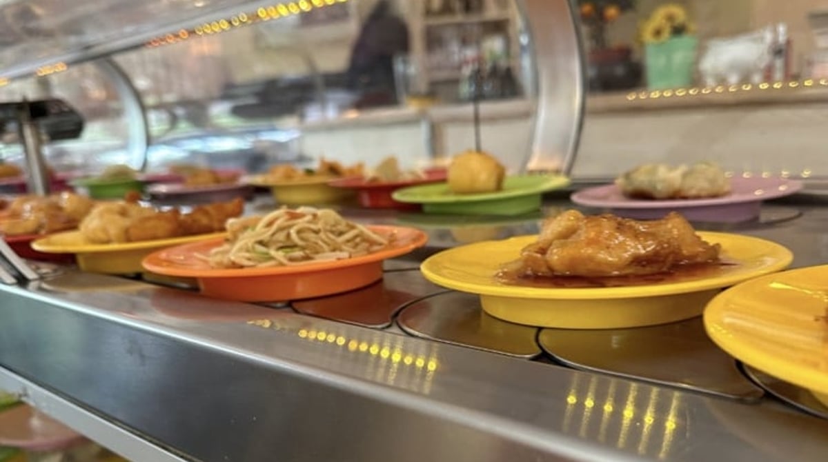 Förderband im Kyoto Running Sushi mit Gerichten auf bunten Tellern