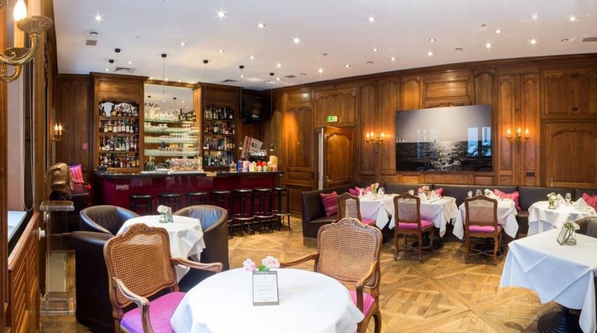 Die Palace Bar im Hotel München Palace mit Holzvertäfelung, Tresen und gedeckten Tischen
