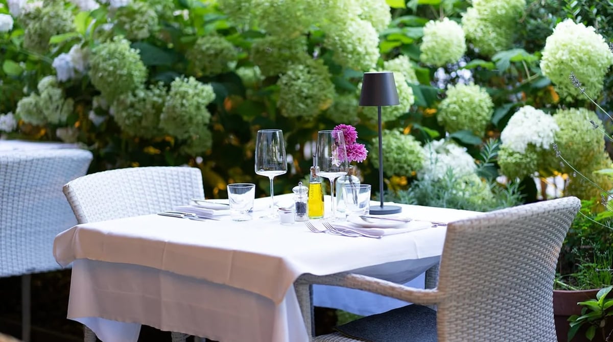 Gedeckter Tisch auf der Terrasse des PURO bar e cucina vor blühenden Hortensien