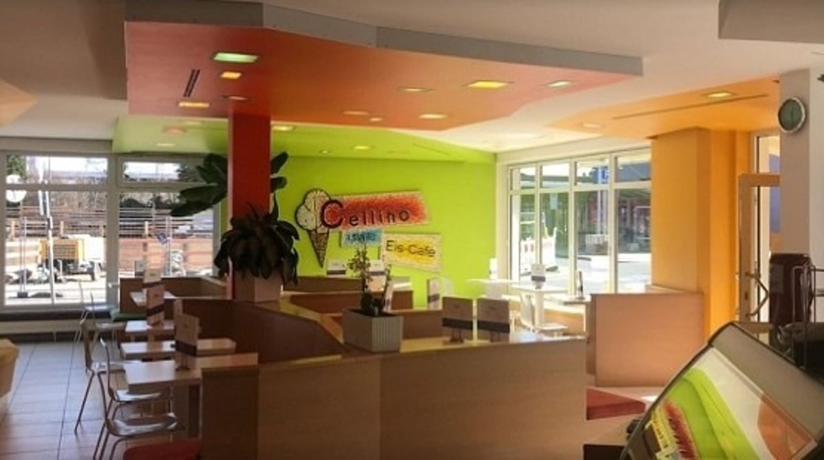 Heller Gastraum des Eis Cafe Cellino in Feldmoching mit grüner Wand, Cellino-Logo und Eistheke
