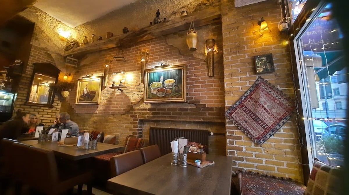 Gastraum des Dehbaschi mit Backsteinwänden, persischem Teppich und Holztischen