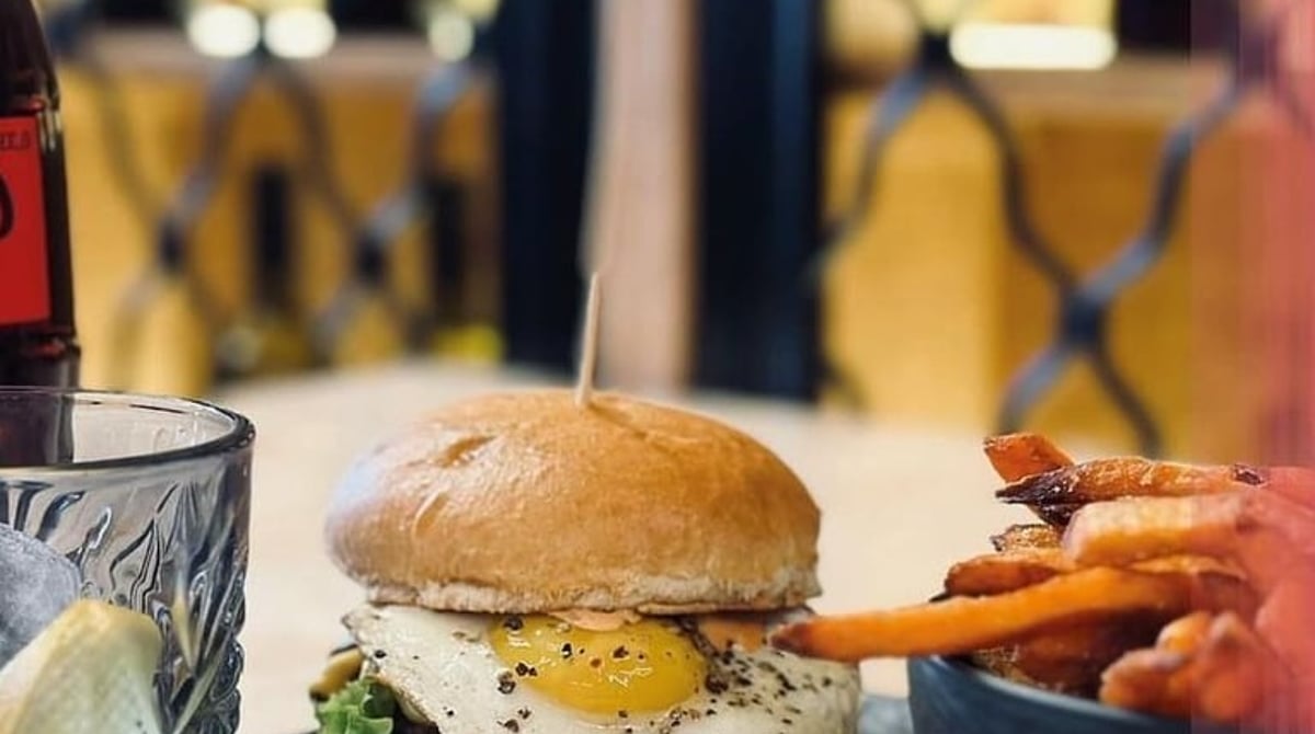 Burger mit Spiegelei und Süßkartoffel-Pommes auf einem Holzbrett