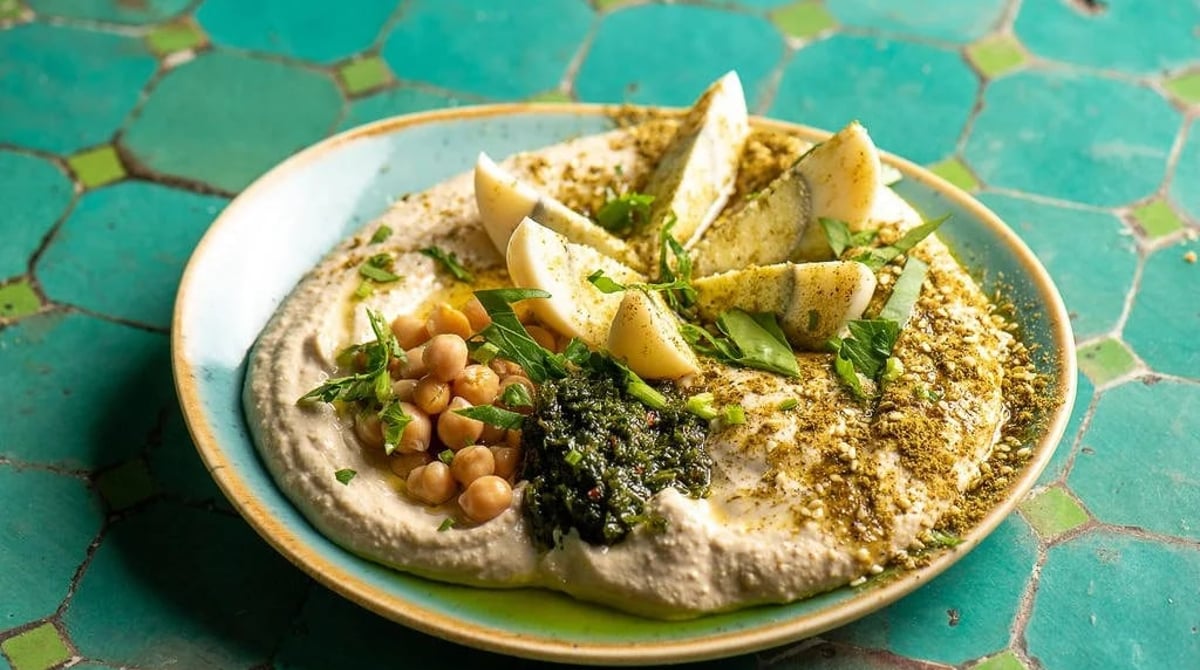 Hummus komplett mit Kichererbsen, Zitrone und Kräutern auf einem Teller im Nana