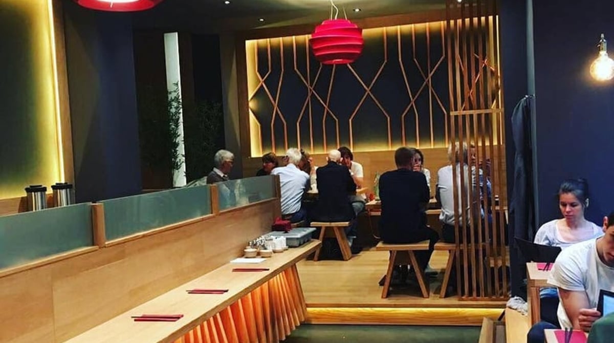 Gastraum des Yuzumuk mit Gästen an Counter und Tischen, rote Pendelleuchten und Holzlamellen