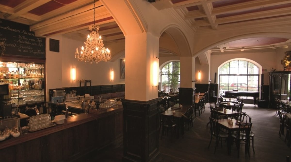 Gastraum des Cafés am Beethovenplatz mit Bar, Kronleuchter und Kassettendecke