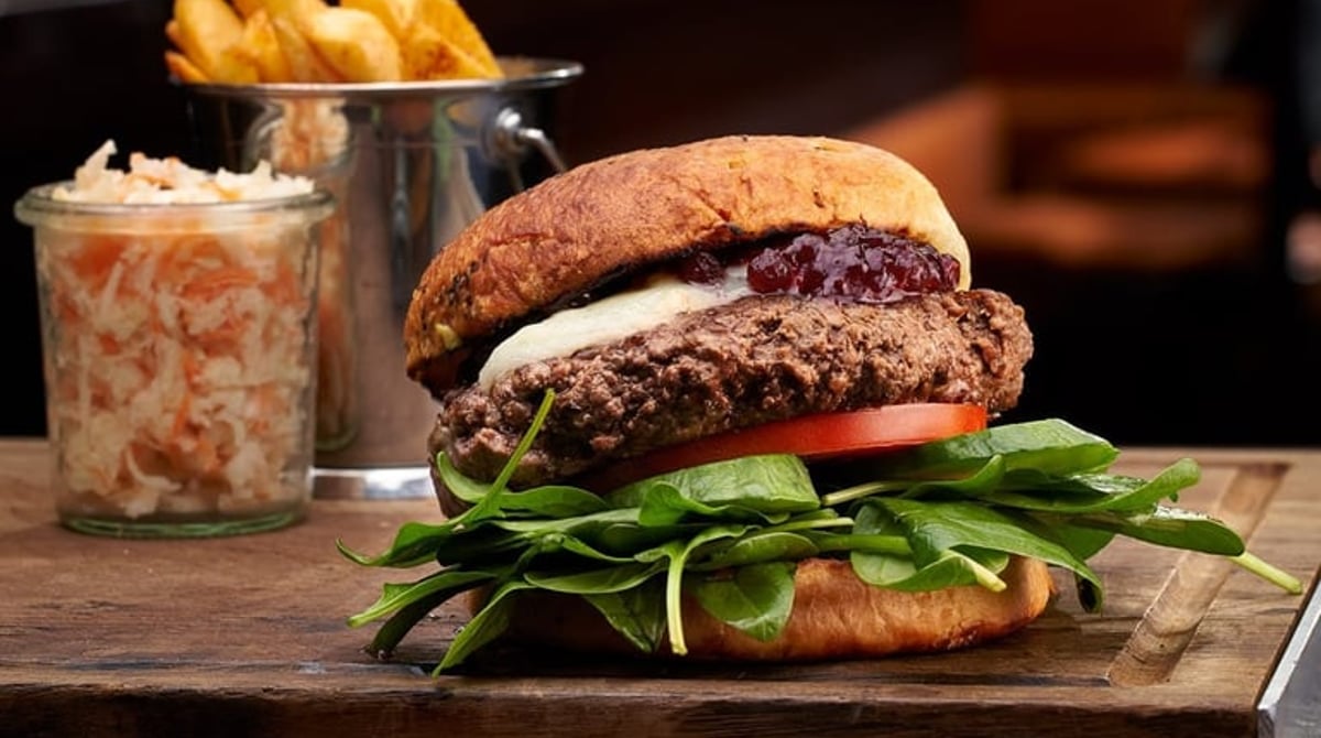 Brie Burger mit Spinat und Cranberrys auf einem Holzbrett in der Drunken Cow
