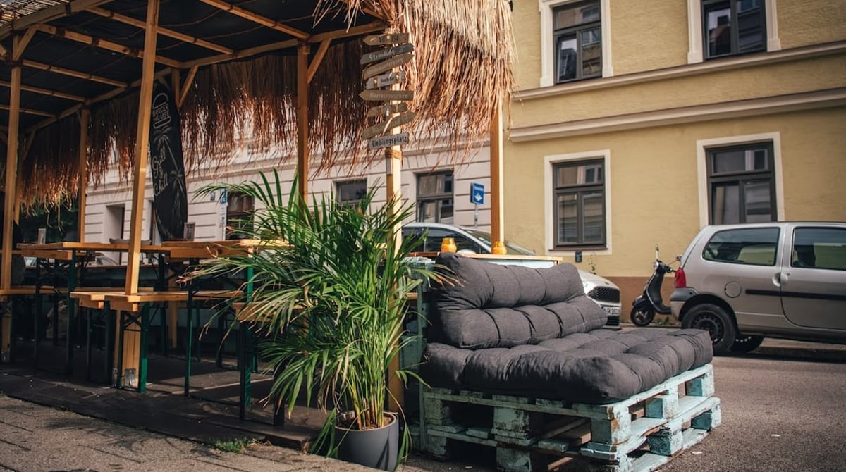 Terrasse unter einem Strohdach mit Palmen und Palettensofa