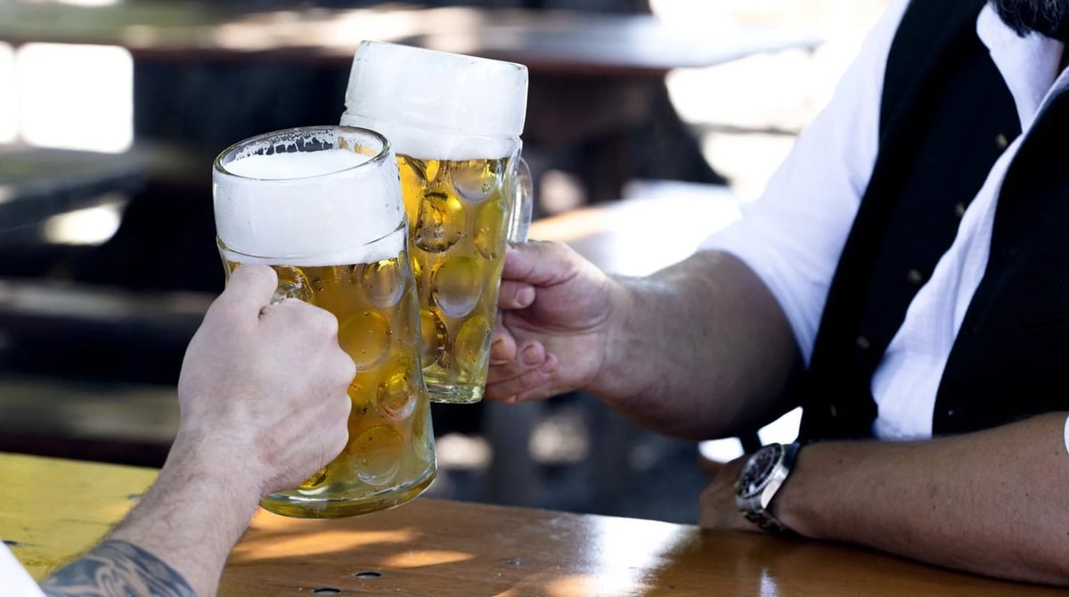 Zwei Männer stoßen mit Maßkrügen im Biergarten des Königlichen Hirschgartens an