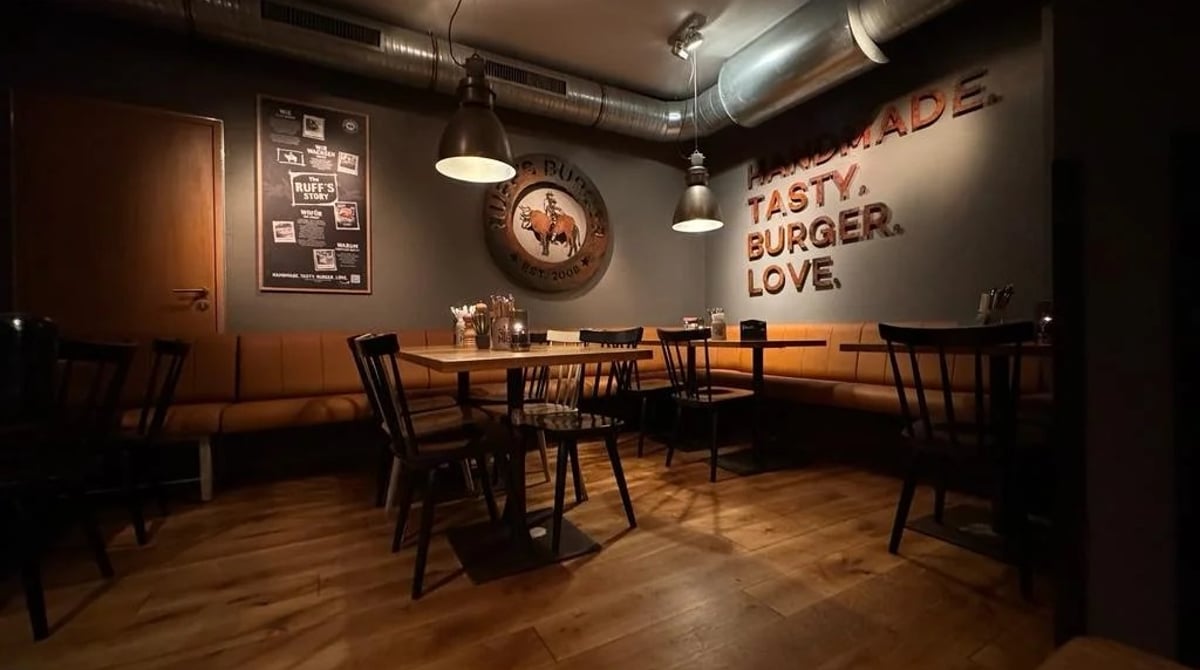 Gastraum von Ruff's Burger mit Polsterbank, Holzstühlen und Schriftzug „Homemade. Tasty. Burger. Love.“ an der Wand