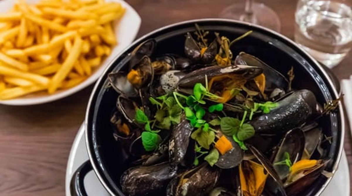 Miesmuscheln im Topf mit Pommes frites und Weingläsern