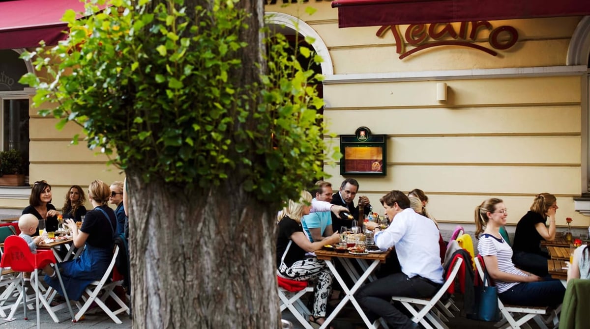 Gäste sitzen draußen vor dem Teatro unter einem Baum