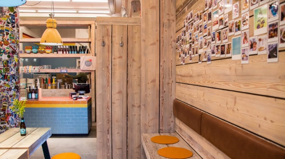 Gastraum von Aloha Poke in der Türkenstraße mit Holzwänden, Sitzbank, bunter Theke und einer Wand voller Polaroids