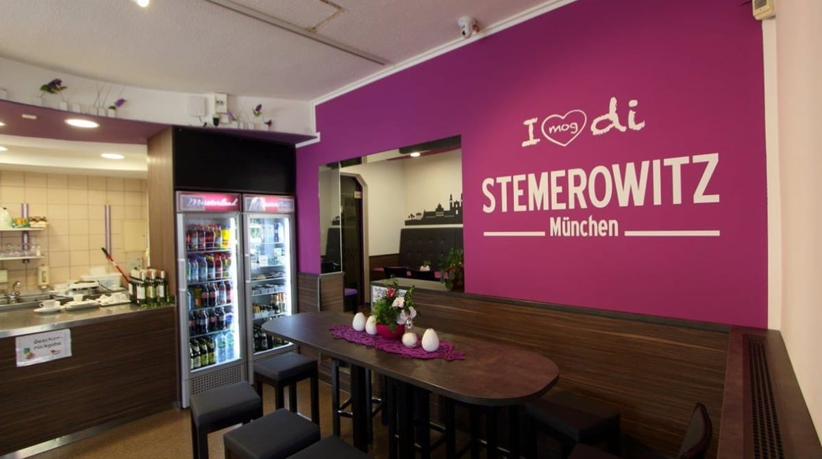 Stehtisch vor der lila Wand mit Stemerowitz-Schriftzug, daneben die Theke