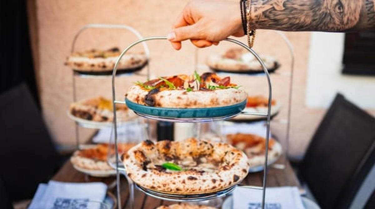 Pizza Étagère mit drei kleinen Pizzen auf einem Holztisch im Casa Nostra
