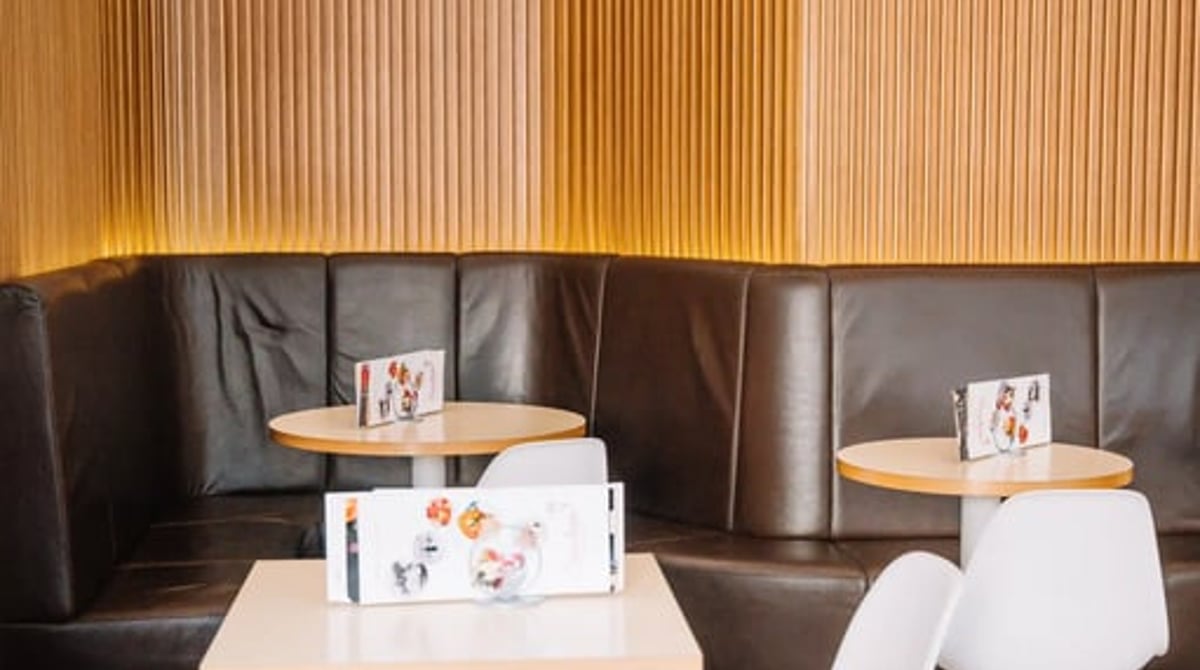 Sitzecke mit Lederbank, runden Tischen und weißen Stühlen im Eiscafé Sarcletti