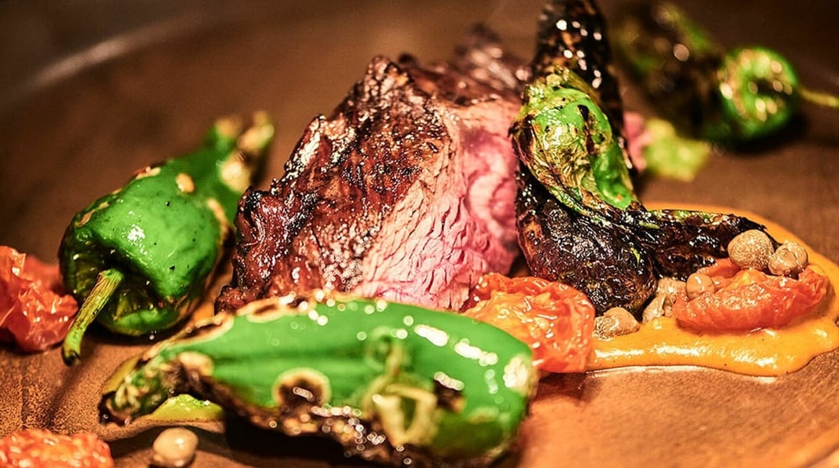 Gegrilltes Fleisch mit grünen Pimientos und Tomaten auf einem Teller
