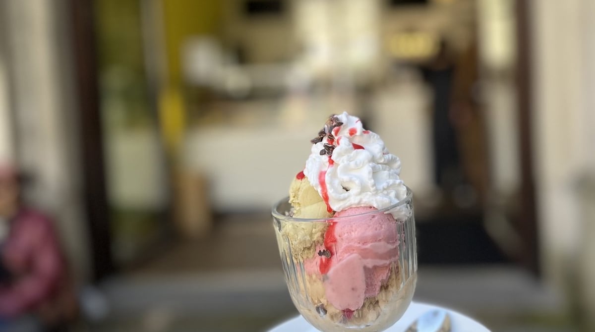 Eisbecher mit Erdbeer- und Bananeneis, Sahnehaube und Kakaonibs vor dem Eingang von Keep Banana