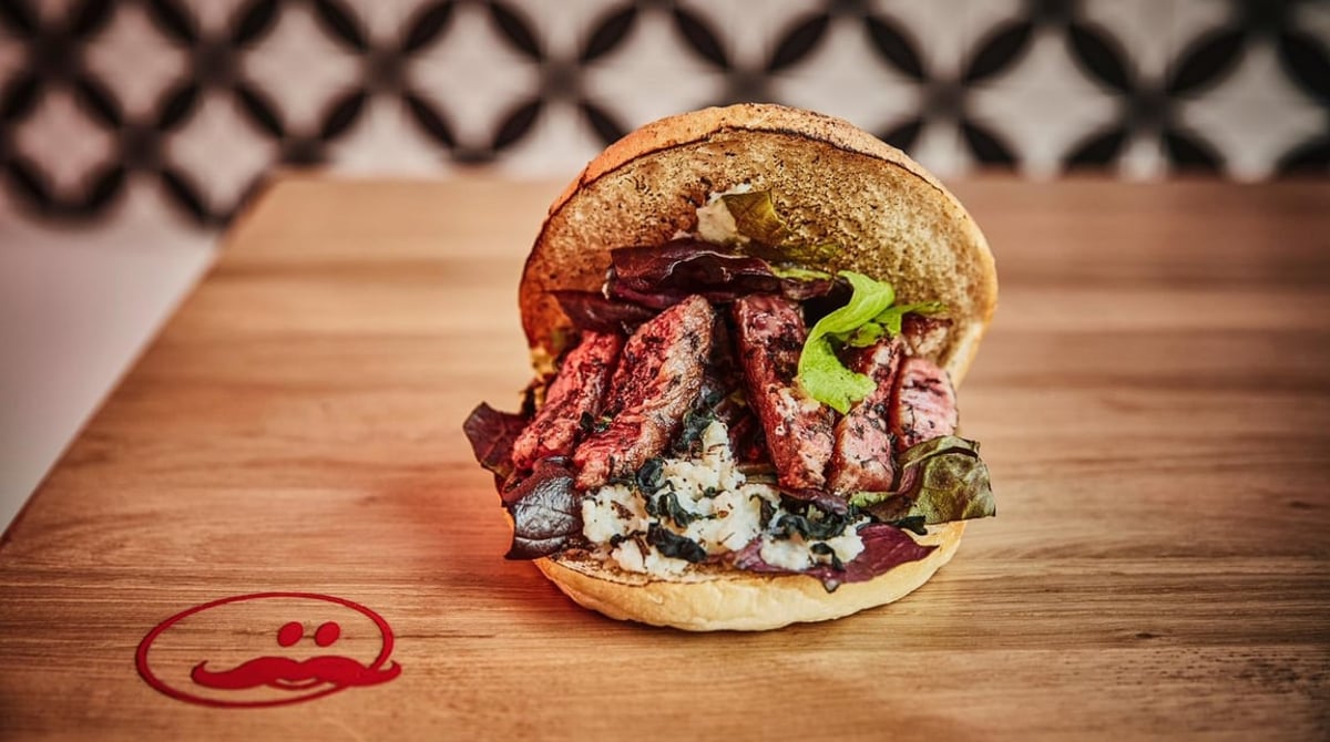 Döner im knusprigen Dönerbrot mit Fleisch und Salat auf einem Holzbrett bei Hans Kebab