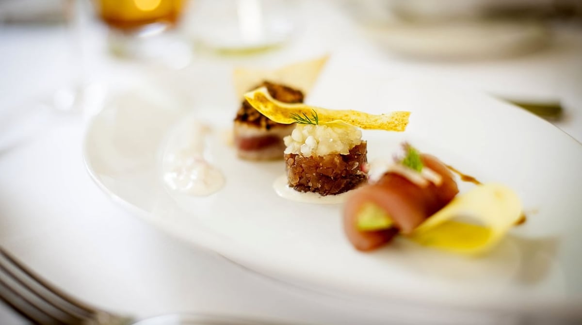 Angerichtete Vorspeise mit Fisch und Tatar auf einem weißen Teller
