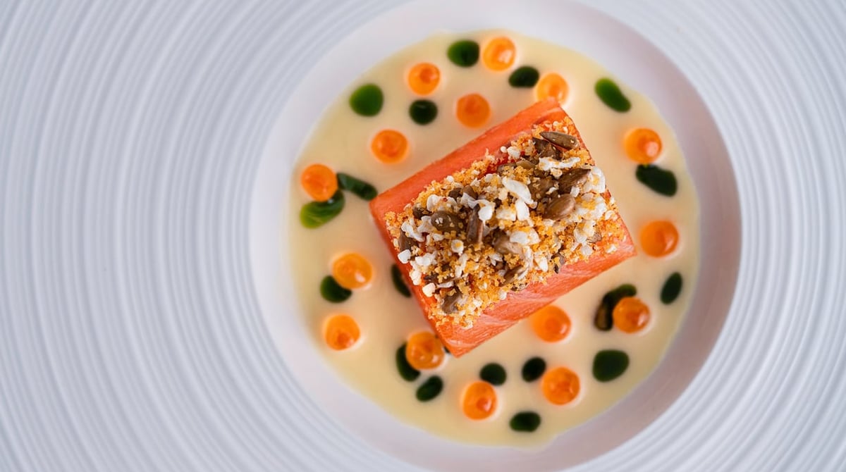 Fischfilet mit Kruste in heller Sauce mit Karottenkugeln und grünen Tupfern