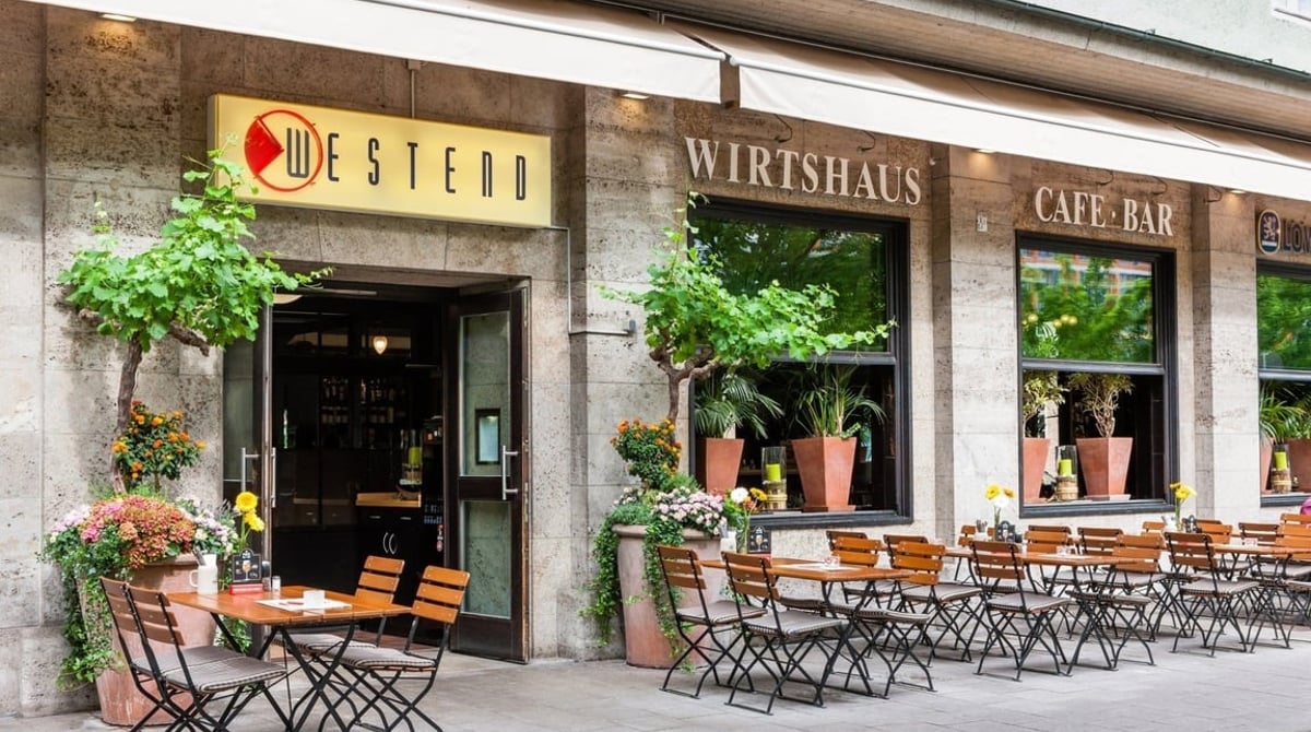 Fassade des Café Westend mit Außentischen auf dem Gehweg an der Ganghoferstraße