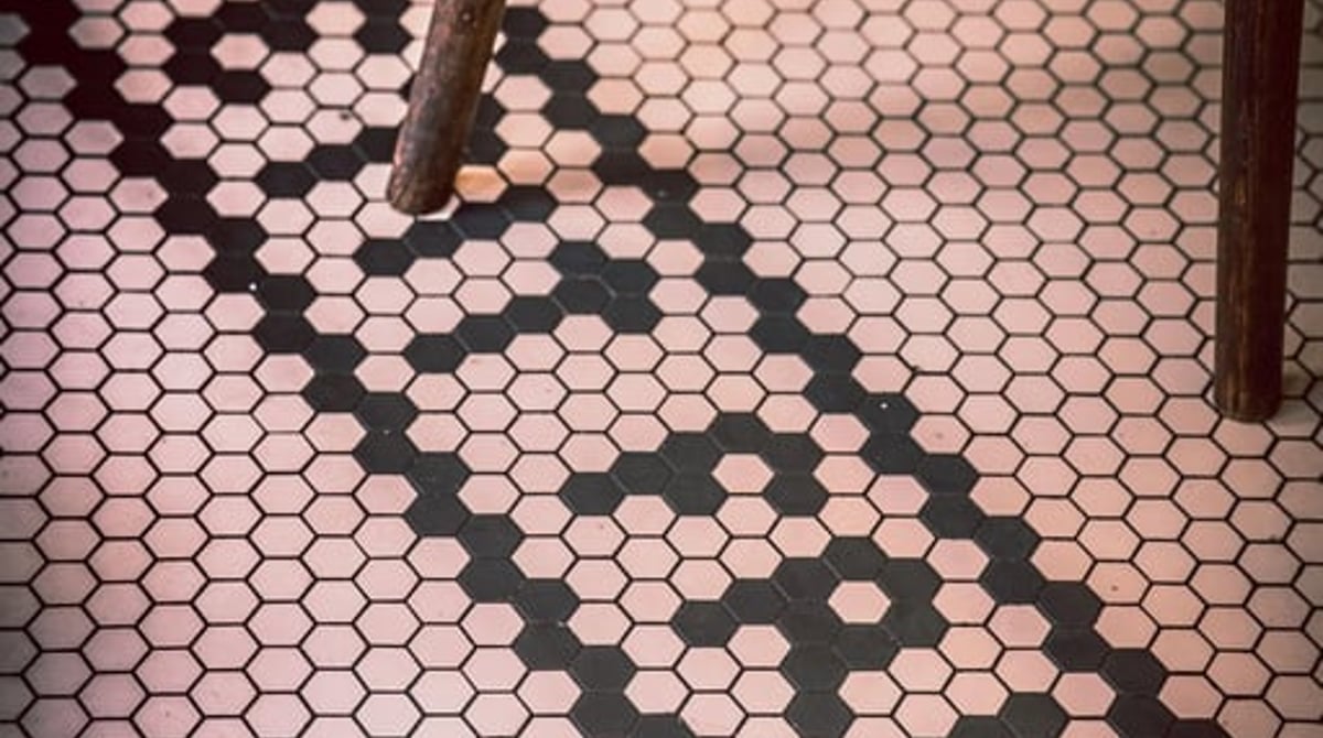Schwarz-weißer Mosaikboden mit dem Schriftzug Petit Fritz und einem Bistrostuhl