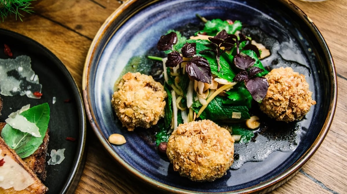 Gebackene Bällchen mit Kräutersalat auf dunkelblauem Teller im the spice bazaar