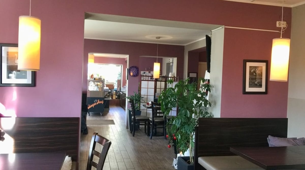Gastraum des Aubinger Herzl in München-Aubing mit dunklen Holzstühlen, violett gestrichener Wand und Durchgang zum Nebenraum
