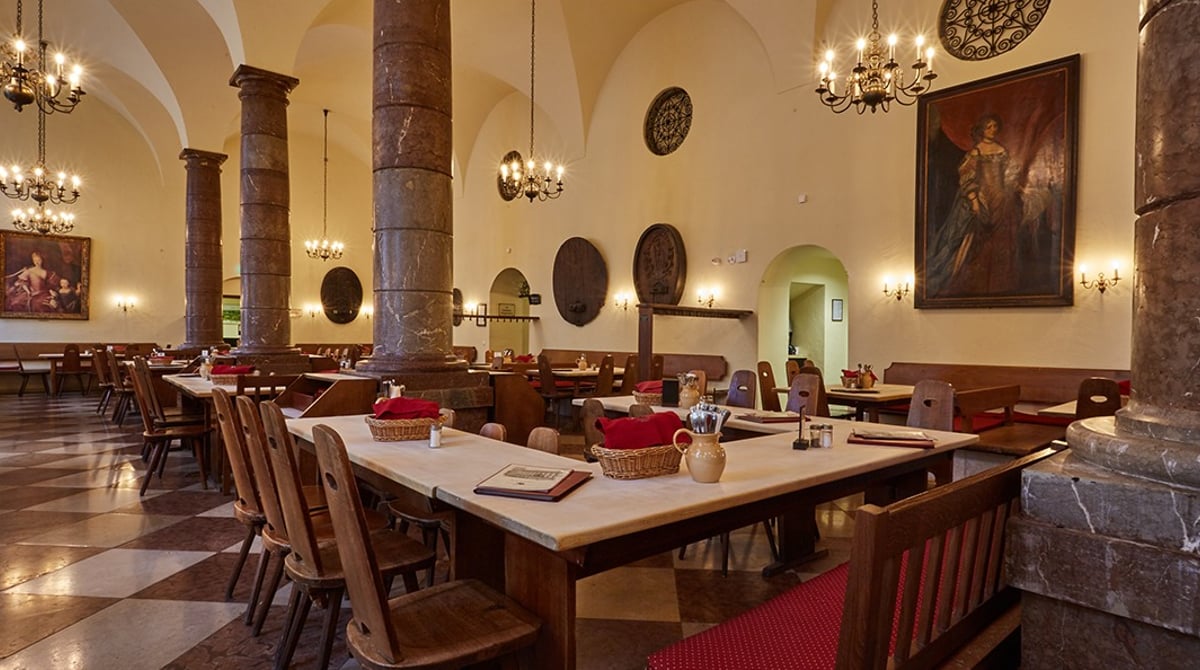 Gastraum mit Säulen, Kronleuchtern und Tischen in der Pfälzer Residenz Weinstube