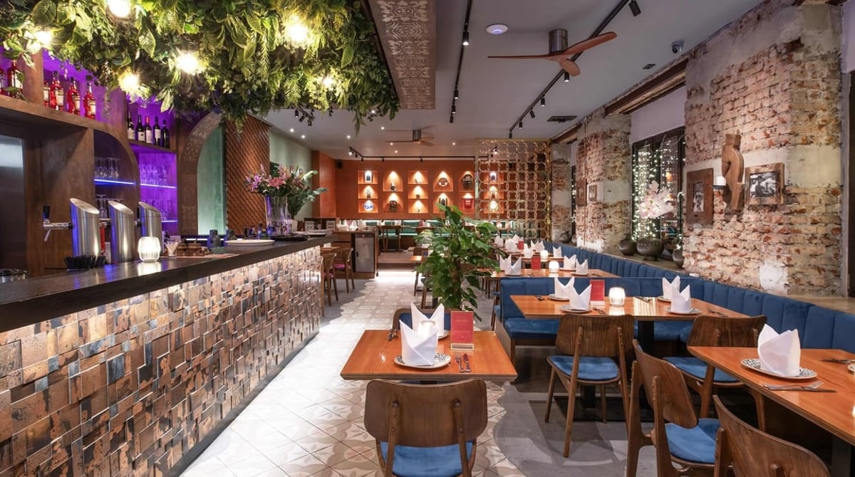 Langer Gastraum des Dhaba mit grünem Blätterdach an der Decke und Backsteinwand