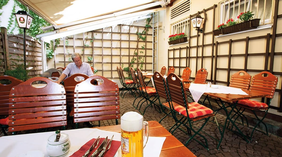 Überdachte Terrasse mit Holzstühlen und einer Maß Bier im Zum Dürnbräu